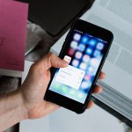 Bàn tay nhấn giữ biểu tượng ứng dụng Gmail trên điện thoại, minh hoạ thay đổi gửi và nhận email từ tài khoản khác từ tháng 1/2027