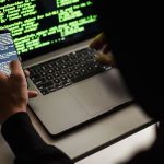 Một người ẩn danh dùng điện thoại và laptop, minh hoạ nguy cơ khi bảo vệ trẻ em trên mạng