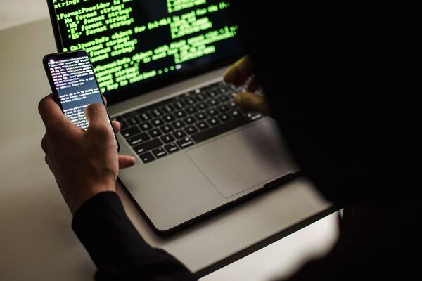 Một người ẩn danh dùng điện thoại và laptop, minh hoạ nguy cơ khi bảo vệ trẻ em trên mạng